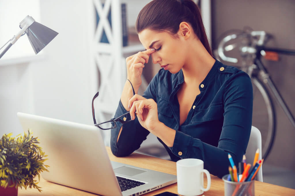 woman looking stressed while sitting at her work desk