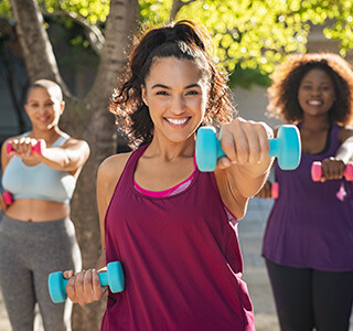 three woman smiling while holding weights