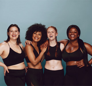 four women smiling in workout clothes