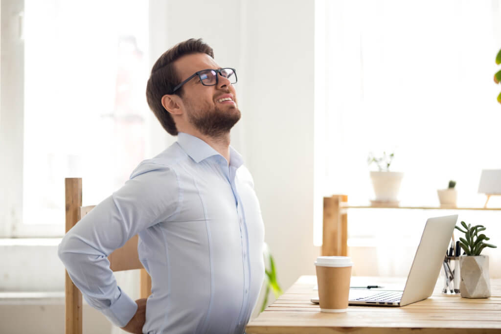 man sitting at desk in pain with a sore back
