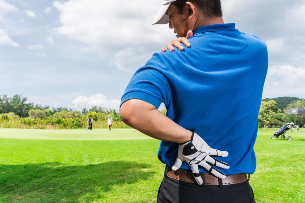 male golfer holding his shoulder and lower back in pain