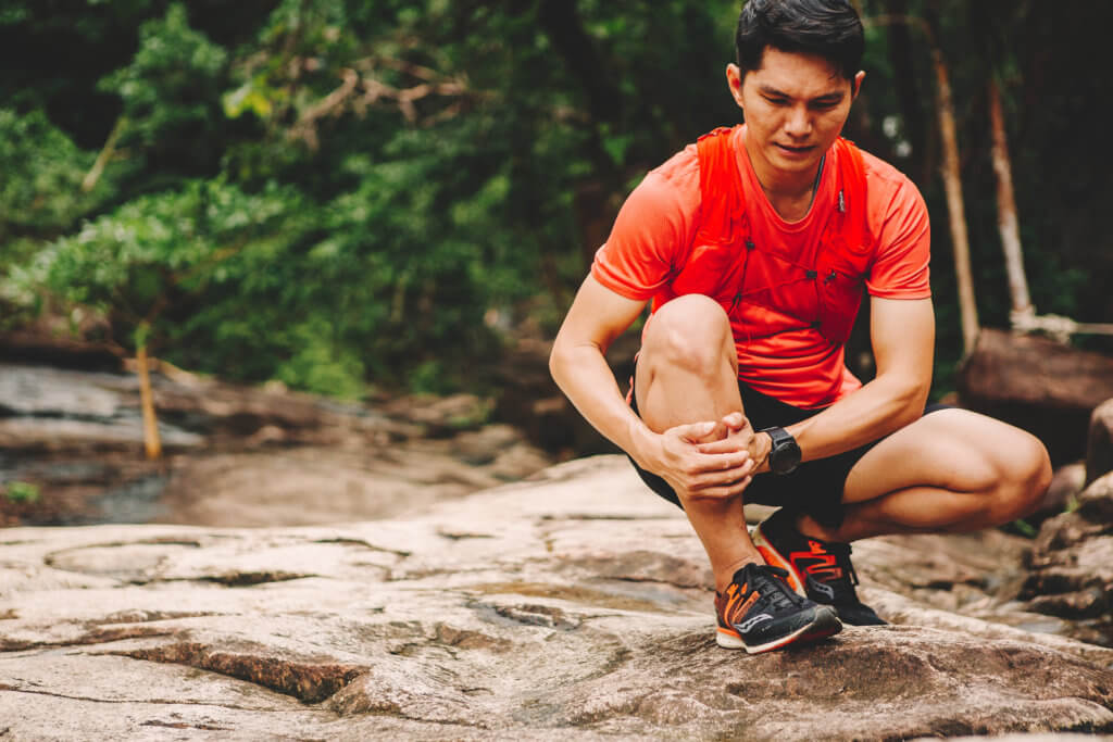 man clutching his shin after running