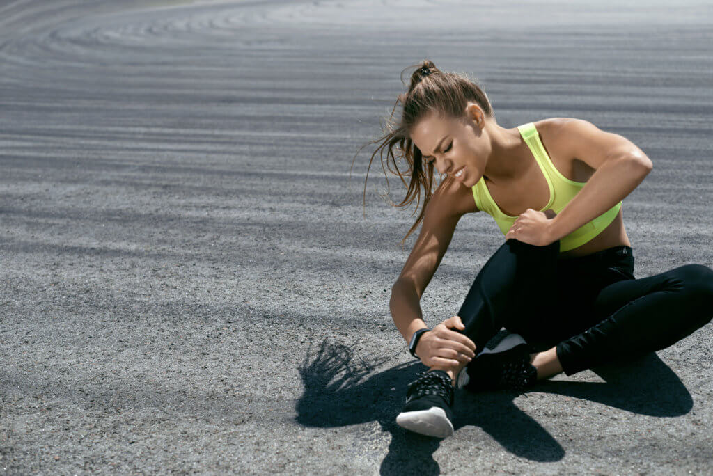 woman holding onto her ankle after running