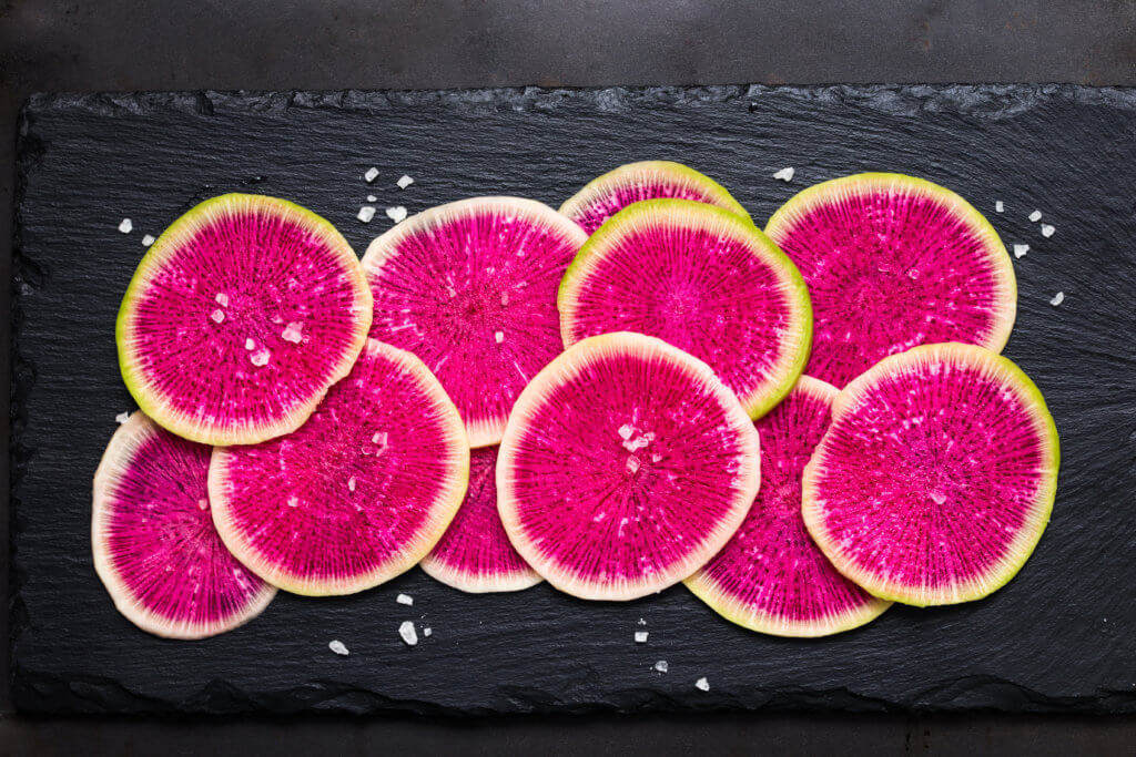 pink watermelon radishes on wood