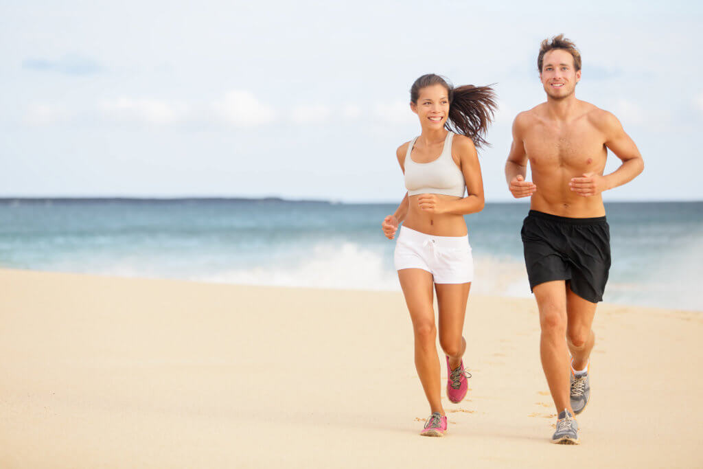 man and woman run on beach