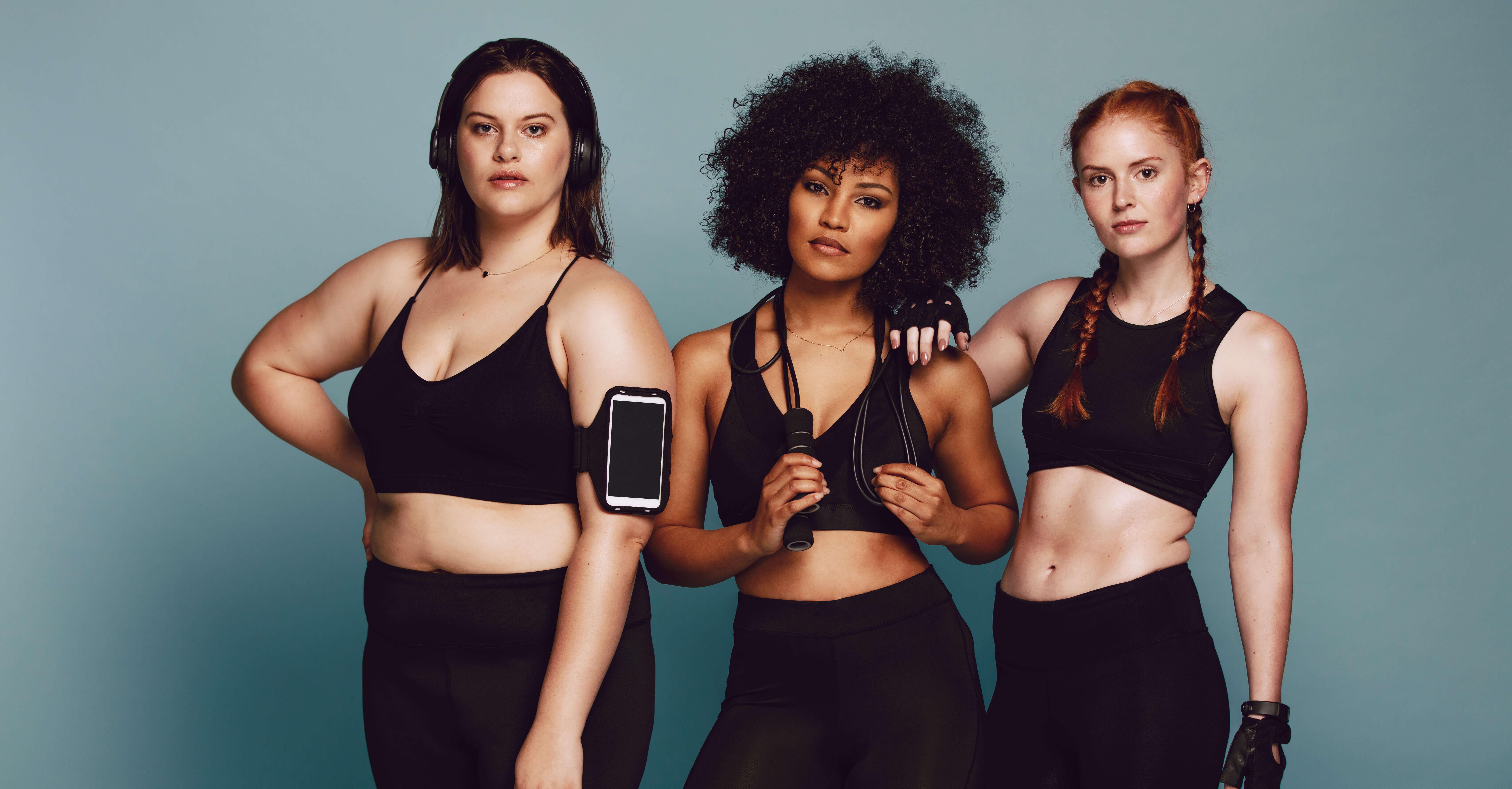 three woman posing with exercise equipment