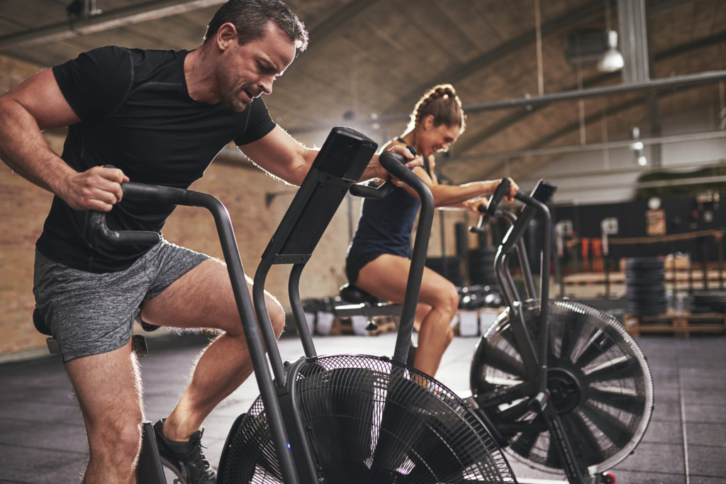 man and woman cycle on indoor bikes