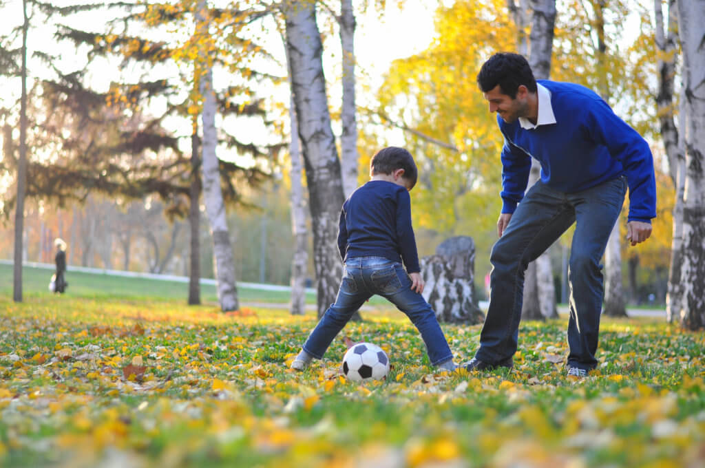 man and son play soccer in the fall