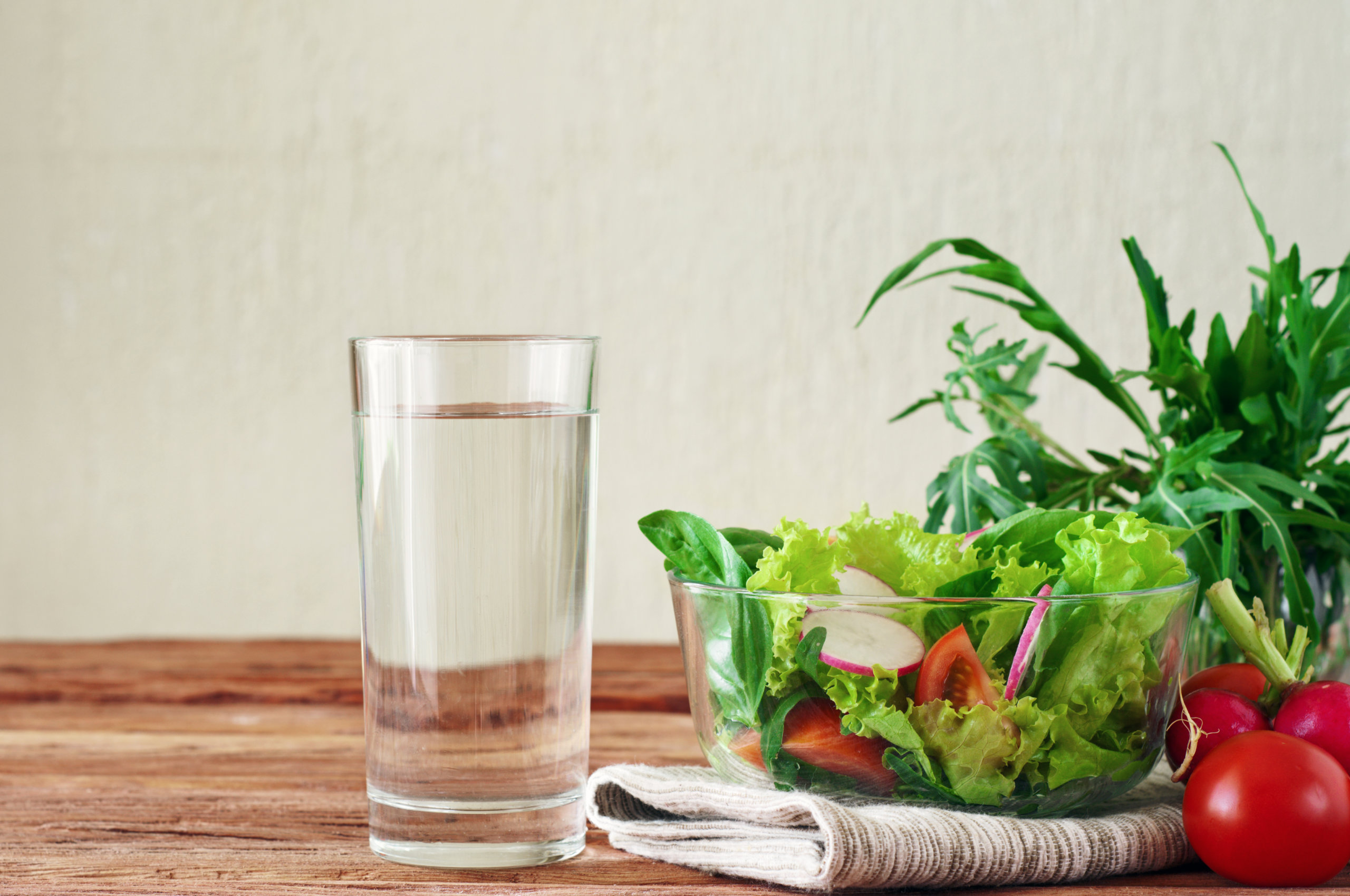 glass of water on table next to salad